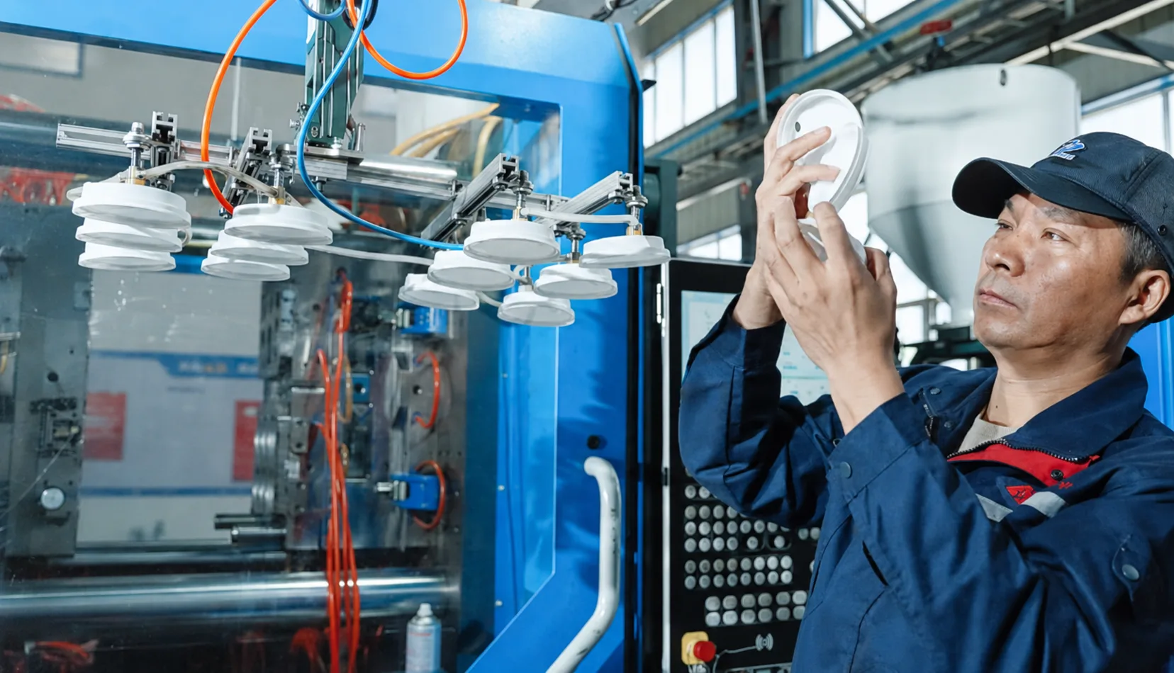 Hengqi quality inspector checking thin-wall moulded products beside the trial machine